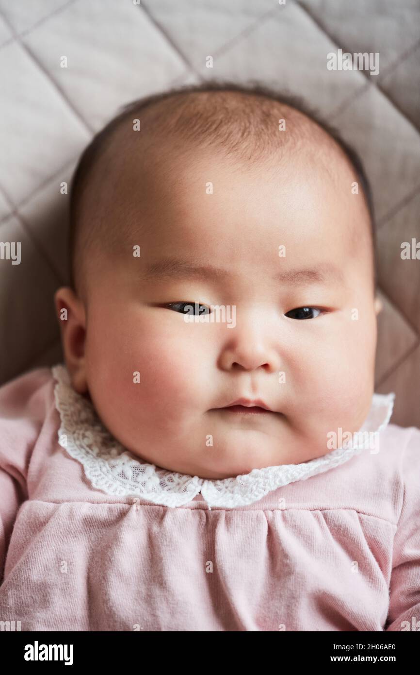 Ritratto di ragazza asiatica cute neonato in bel vestito rosa che giace sul letto Foto Stock