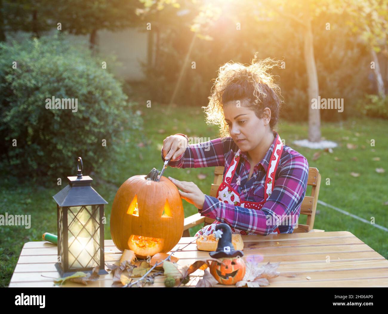 Bella giovane donna che prepara il jack testa di zucca per Halloween in giardino Foto Stock