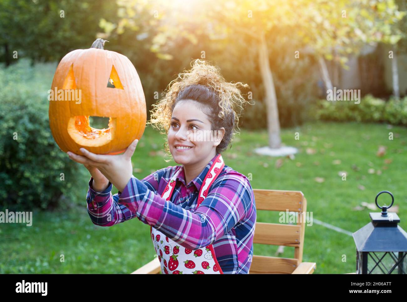 Bella giovane donna che prepara il jack testa di zucca per Halloween in giardino Foto Stock