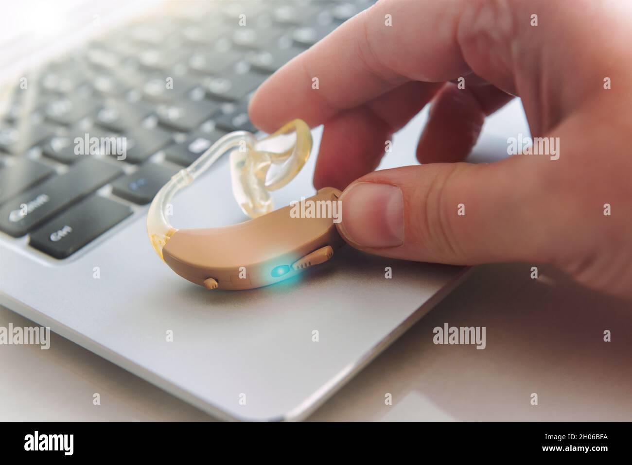 La mano della donna raggiunge per un'aria uditiva sul laptop Foto Stock