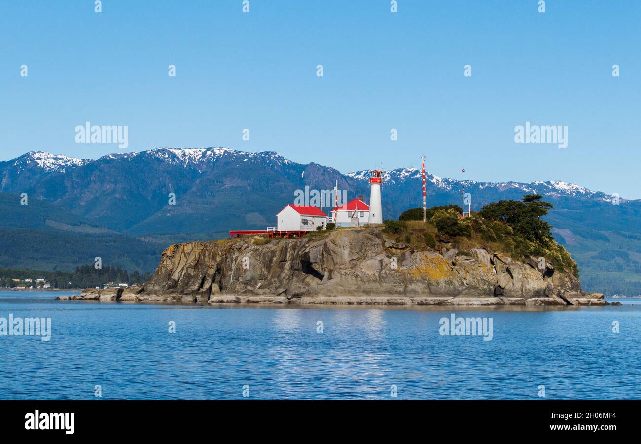 Supportato da montagne innevate sull'isola di Vancouver, lo storico Chrome Island Lightstation si affaccia sullo stretto della Georgia sulla costa occidentale del Canada. Foto Stock