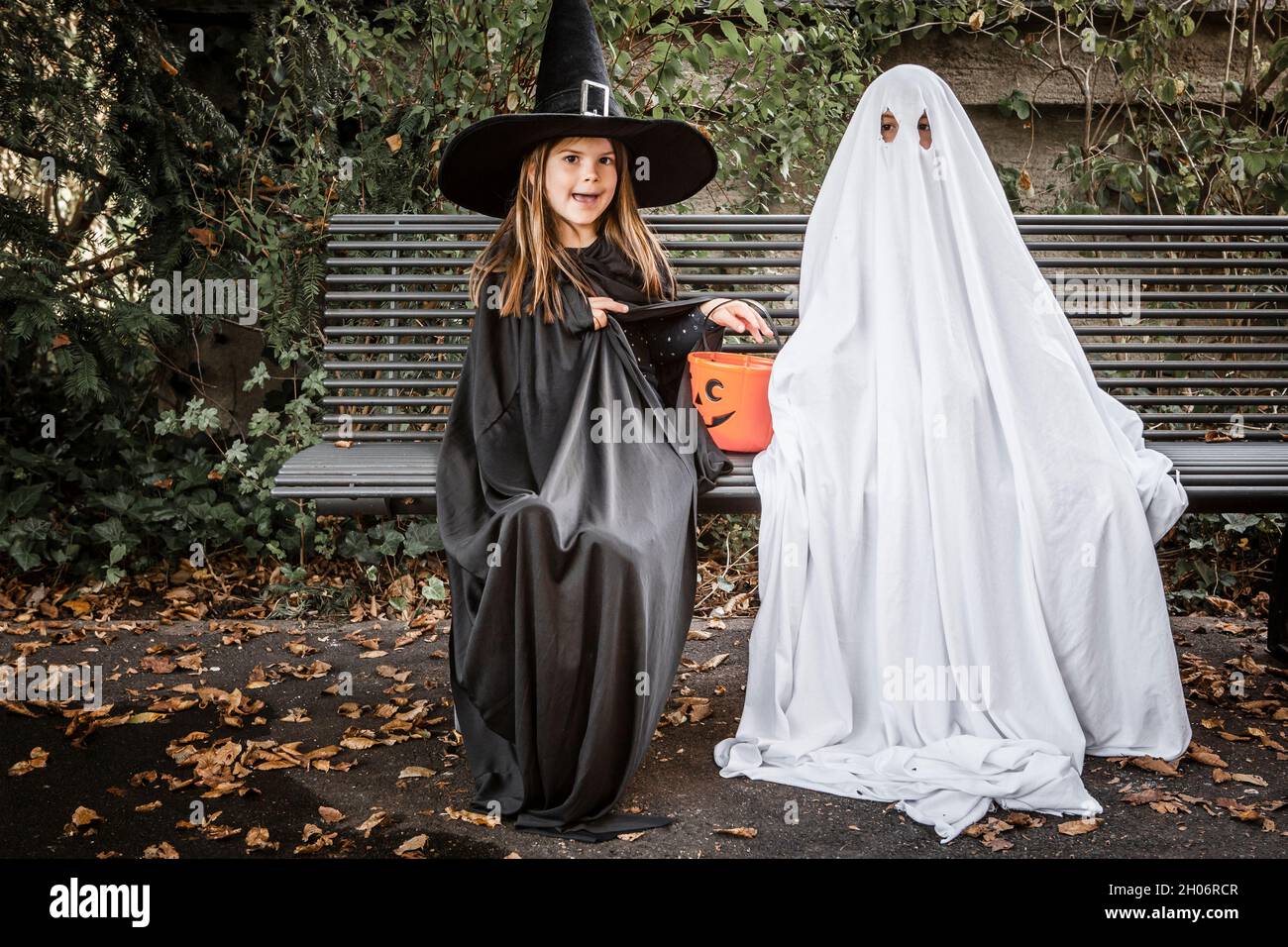 Giovane ragazzo vestito in un lenzuolo per essere un fantasma, e una  giovane ragazza in costume da strega che tiene un secchio di zucca per  Halloween Foto stock - Alamy