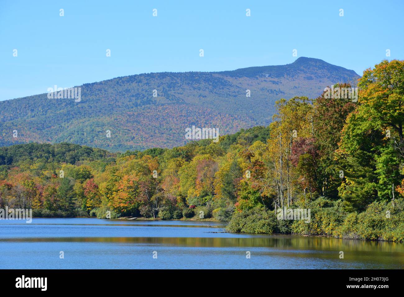 Il Galloway Peak di Grandfather Mountain si innalza sopra Price Lake sulla Blue Ridge Parkway in autunno. Foto Stock