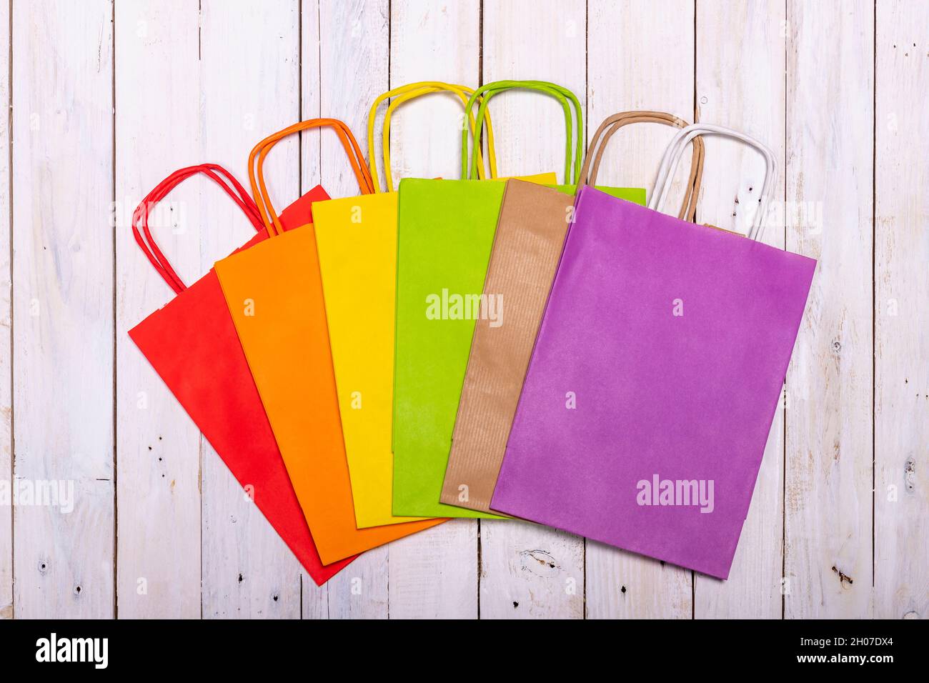 Un arcobaleno di sacchetti di carta colorati su un elegante tavolo di legno  per il vostro shopping gioioso. Spazio per il logo o una scritta sulla  borsa viola Foto stock - Alamy