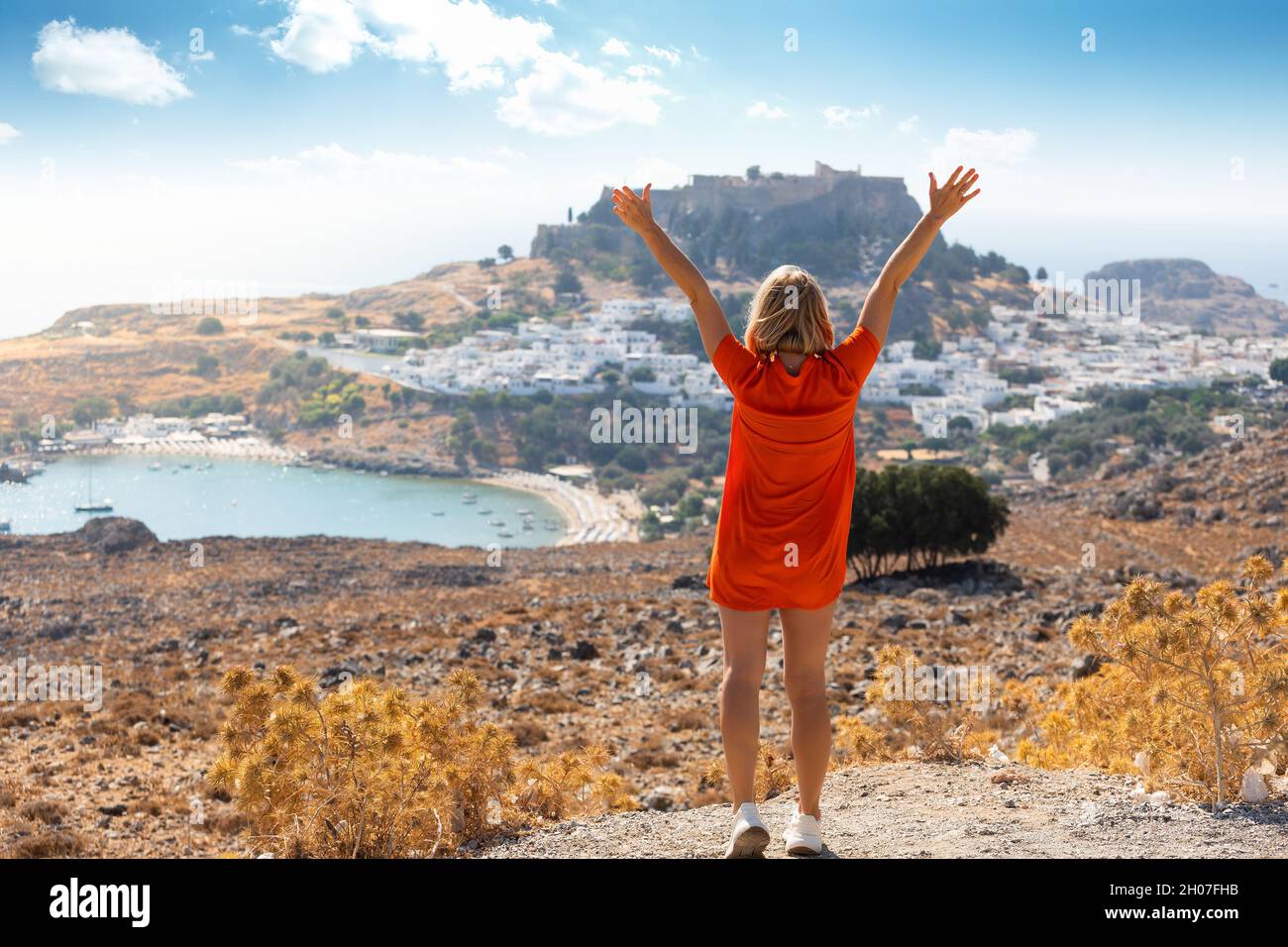 Una donna bionda guarda il panorama di Lindos sull'isola di Rodi, in Grecia Foto Stock