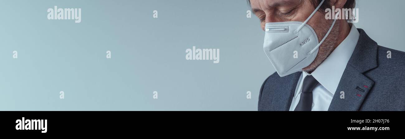 Elegante uomo d'affari che indossa maschera respiratoria protettiva KN95 durante le pandemie di Covid-19, fuoco selettivo Foto Stock