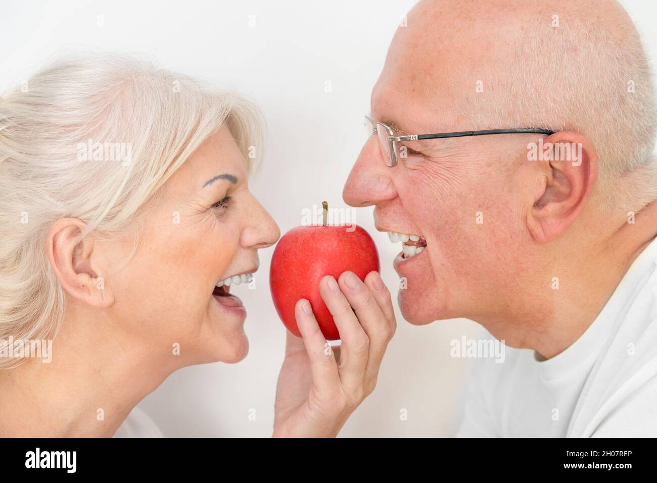 Due persone anziane che detengono una mela. Concetto di denti sani e forti Foto Stock