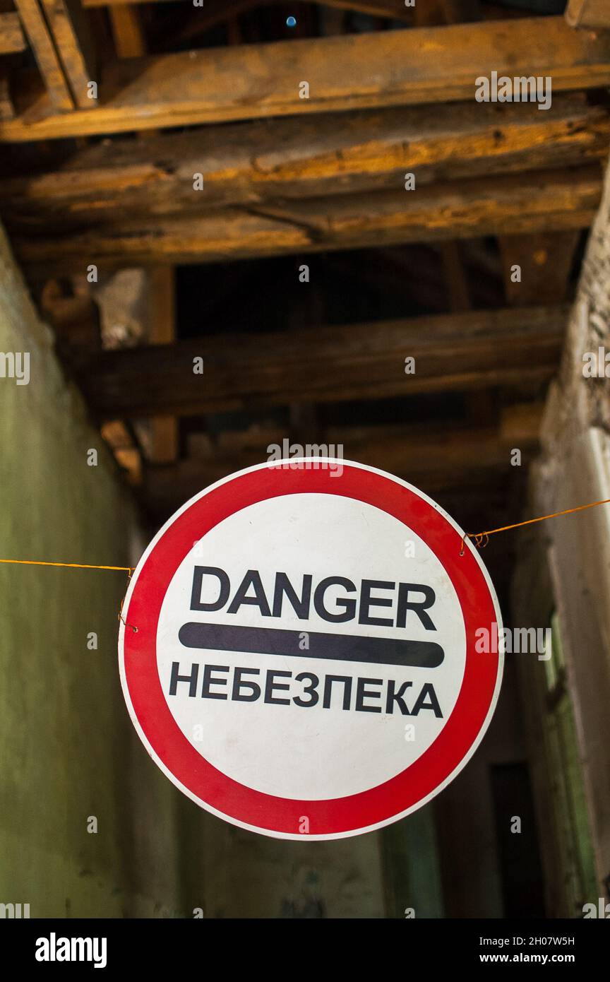 Vecchia casa relitti con 'Danger' in inglese e in segno di avvertimento ucraino, edificio abbandonato, luogo inabitabile Foto Stock