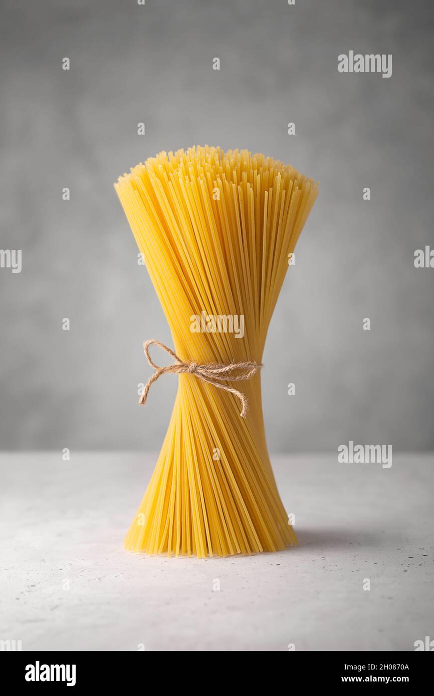Spaghetti crudi. Pasta italiana secca preparata con grano duro, fondo grigio Foto Stock