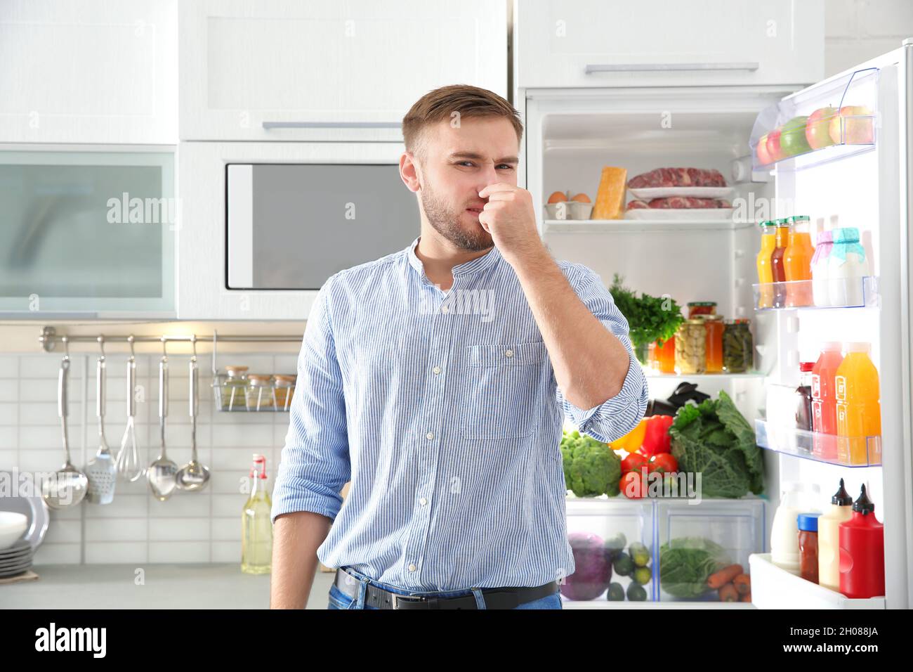 Uomo che sente cattivo odore da prodotti obsoleti in frigorifero a casa  Foto stock - Alamy
