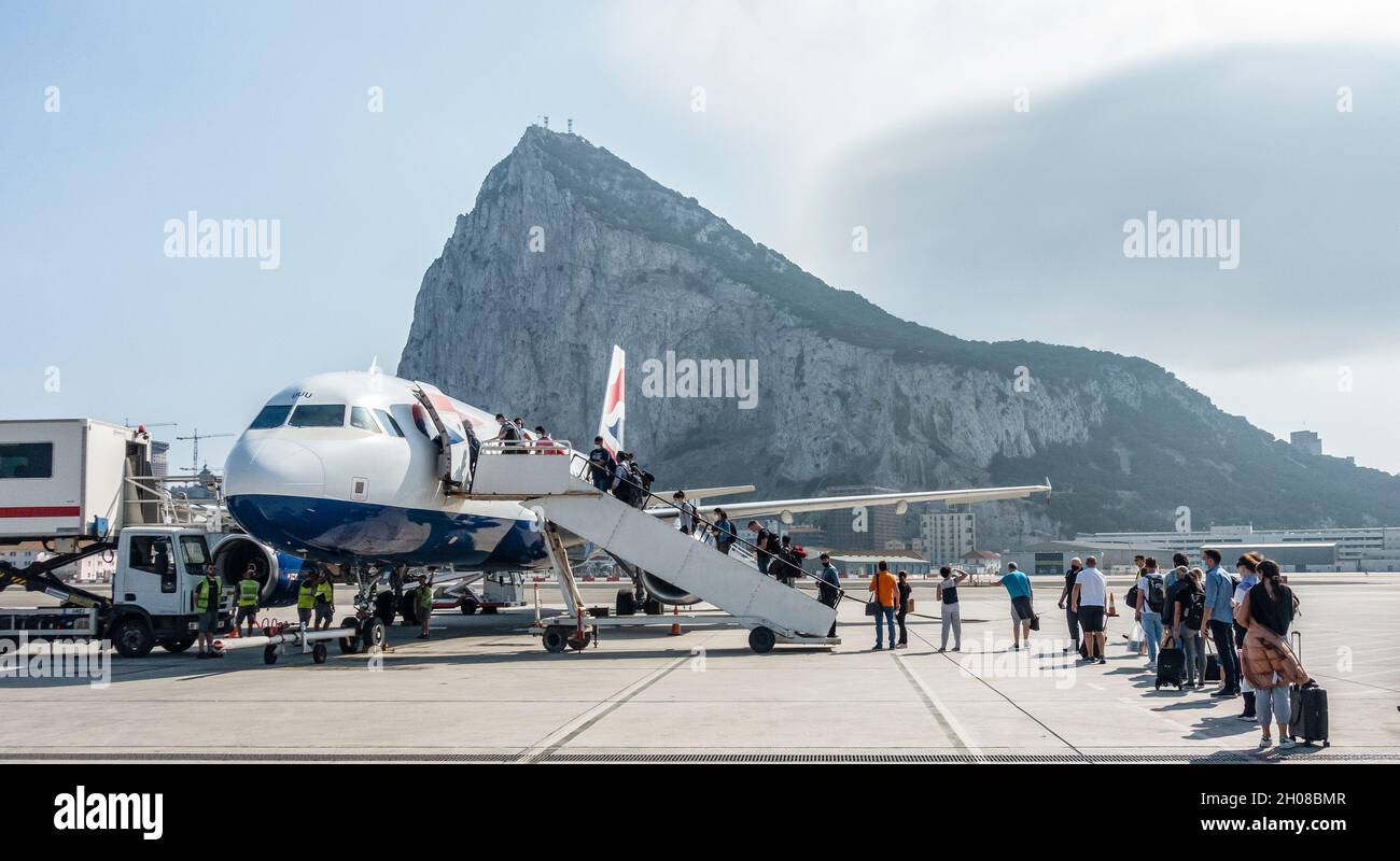 I passeggeri (indossando le maschere) fanno la fila per imbarcarsi su un Airbus British Airways A320-232 che è parcheggiato sul grembiule all'Aeroporto di Gibilterra. Foto Stock