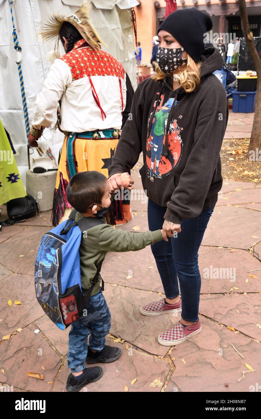 Una donna dei nativi americani e il suo giovane figlio tengono le mani in attesa dell'inizio della celebrazione della Giornata dei popoli indigeni a Santa Fe, New Mexico. Foto Stock