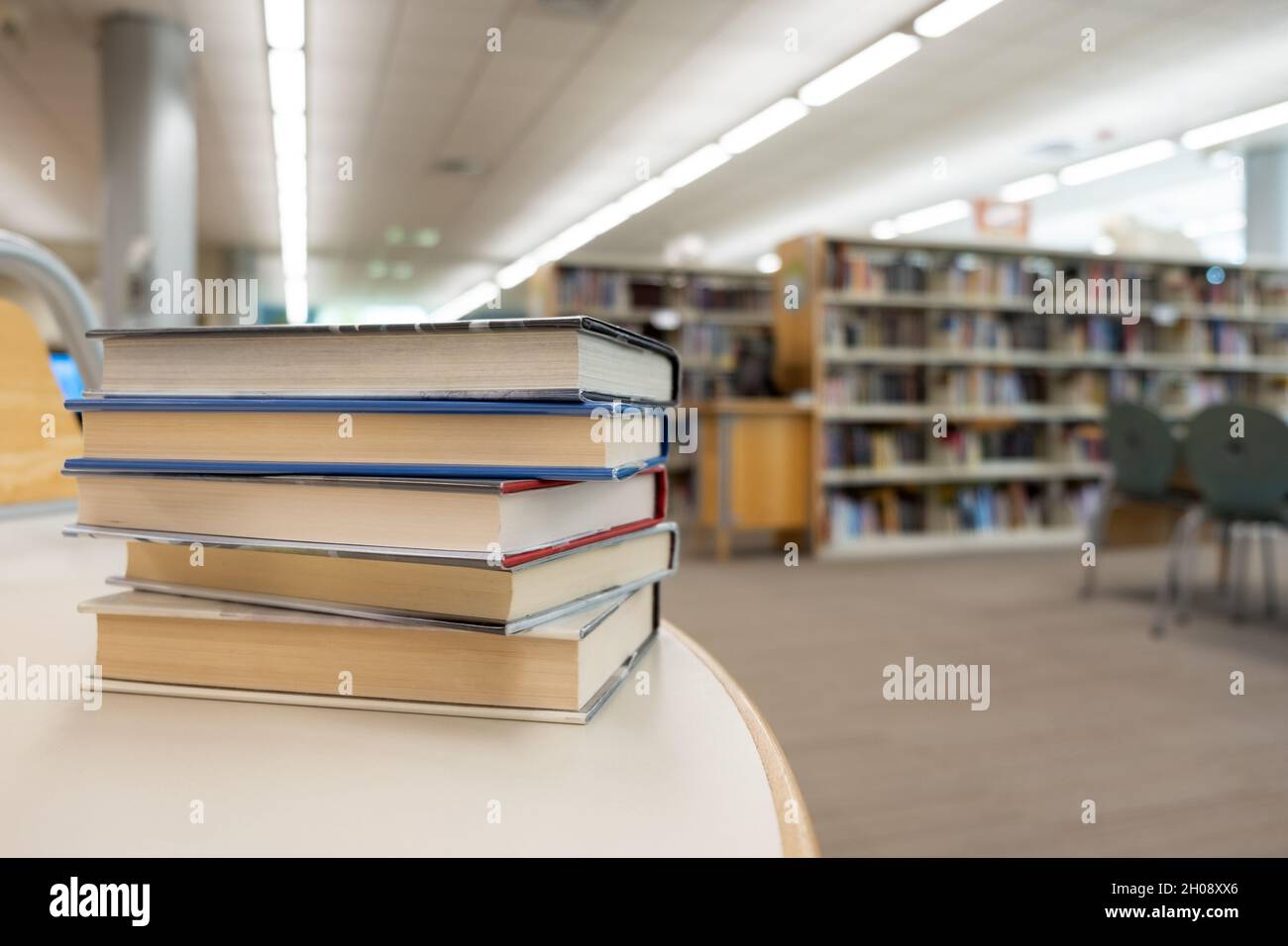 Pila di libri sul tavolo in biblioteca Foto Stock