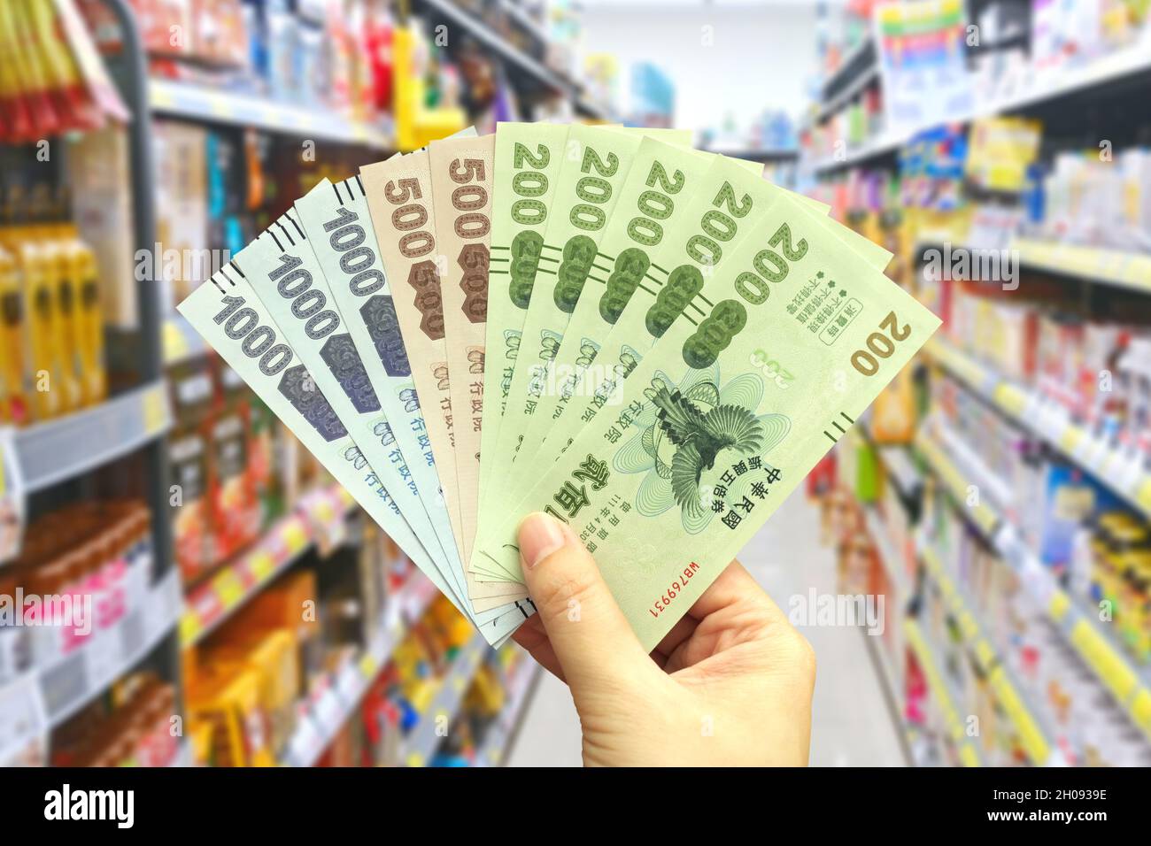 Taipei, Taiwan - Ott 11, 2021 : mano dell'uomo tiene il Quintuple Stimulus Voucher in un negozio di alimentari. Foto Stock