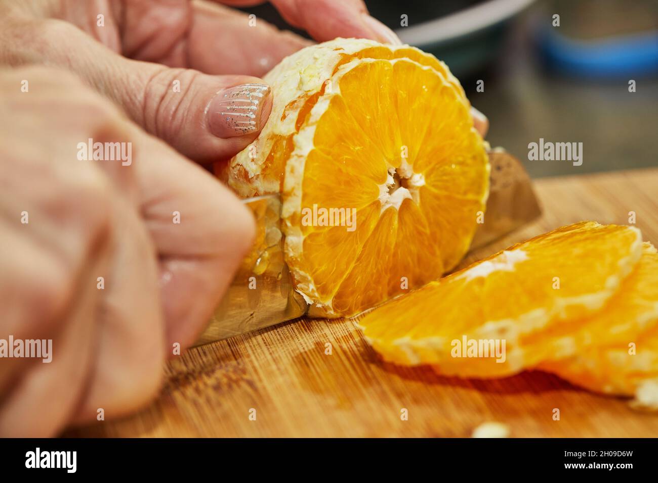 Lo chef taglia l'arancia a fette con il coltello. Foto Stock