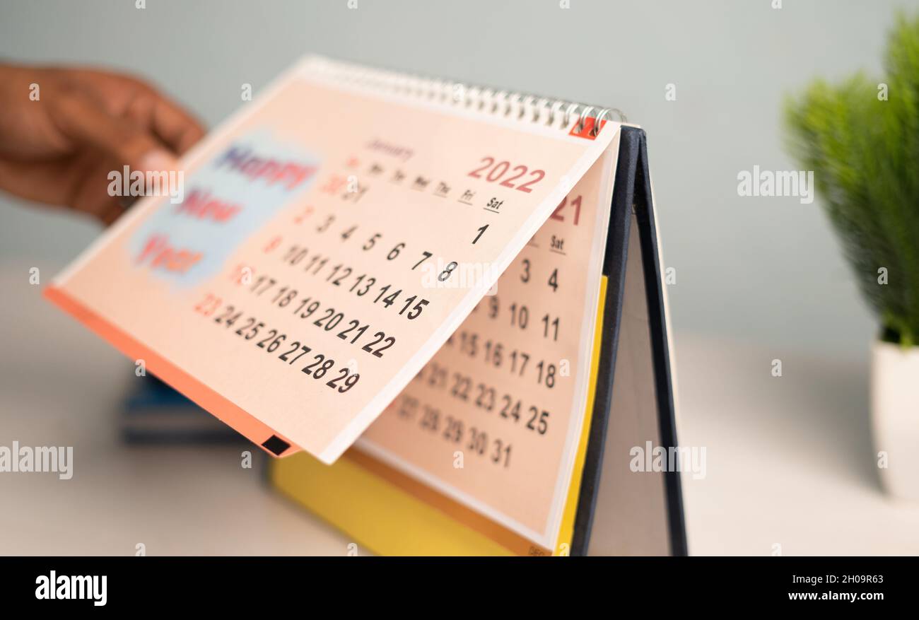 Primo piano delle mani girando il calendario al nuovo anno 2022 da dicembre 2021 - cocept di fine 2021 o inizio del nuovo anno 2022 Foto Stock