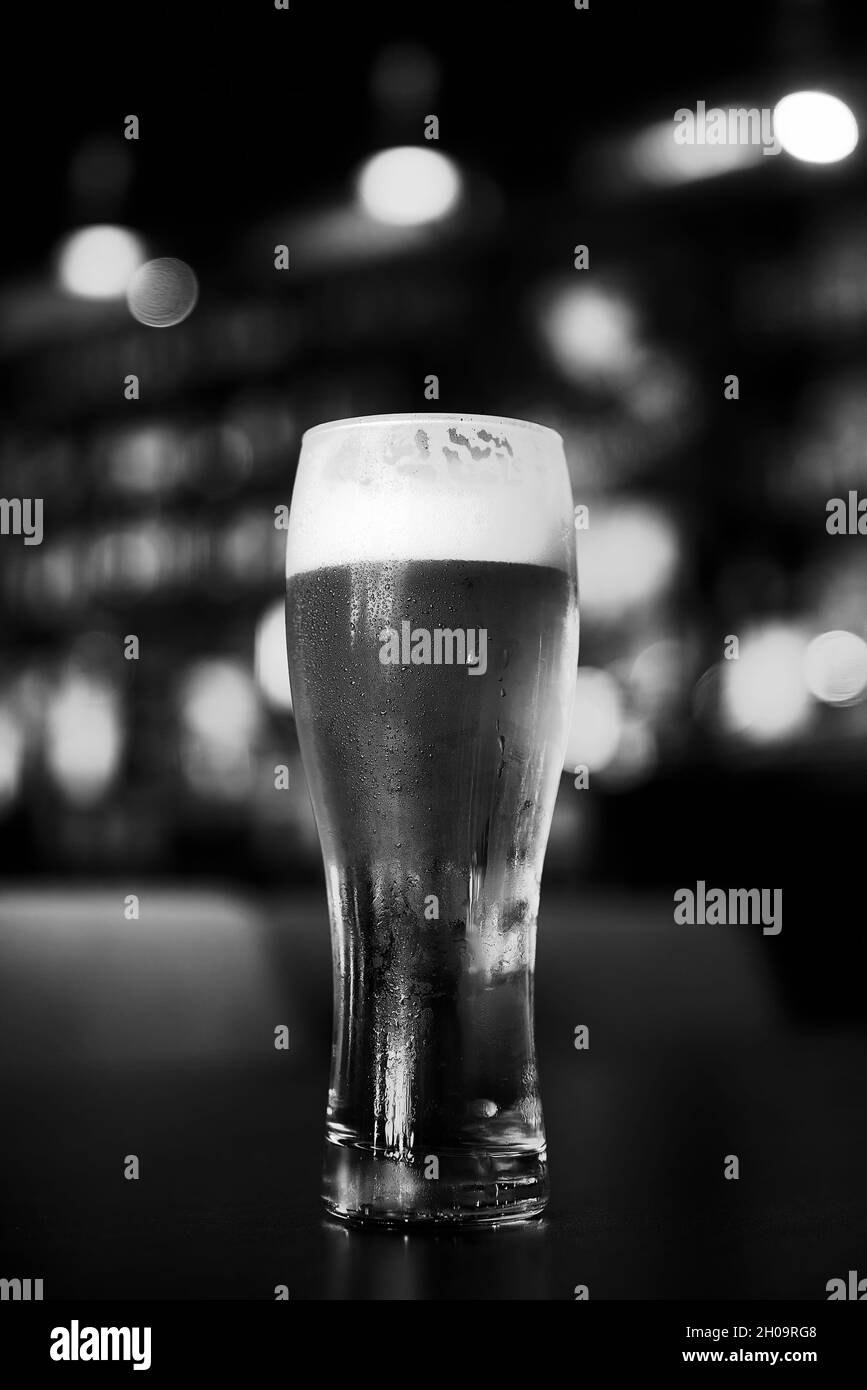 Bicchiere di birra su un tavolo in un bar su sfondo bokeh sfocato. Foto Stock