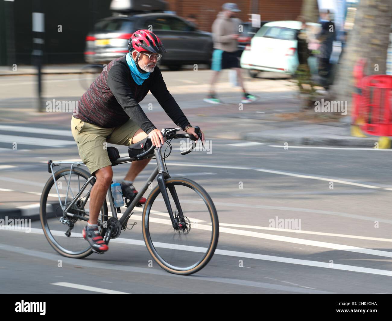 Un uomo in bicicletta su Chiswick High Road, Londra, Regno Unito Foto Stock