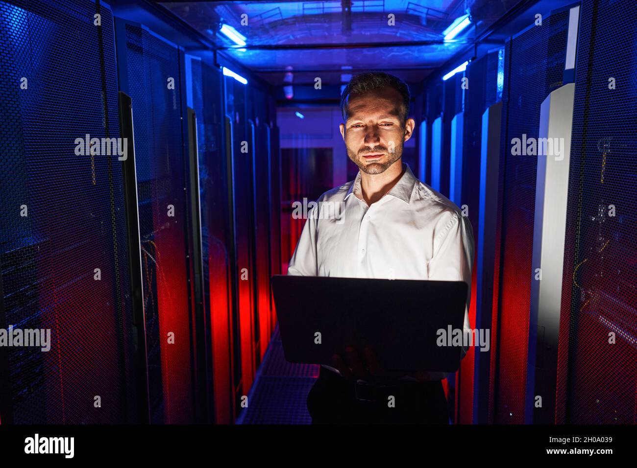 Tecnico IT che lavora con il notebook nel centro di archiviazione dati Foto Stock
