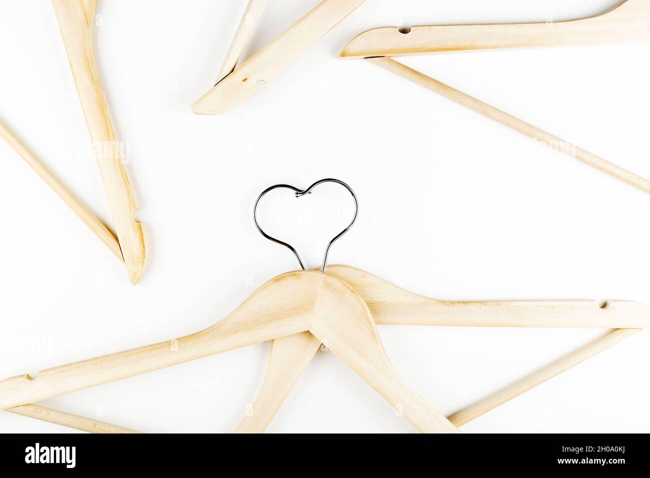 Consumo consapevole concetto di moda lenta. Cuore di appendiabiti intrecciati su sfondo bianco. Foto Stock