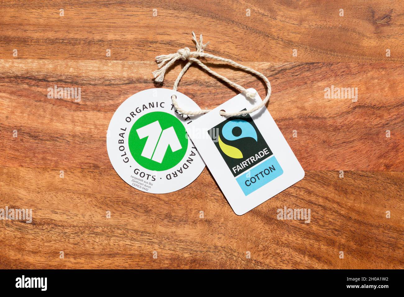 Gauting, Germania - Apr 20, 2021: GOTS (Global Organic Textile Standard) e Fairtrade cotone etichetta su sfondo di legno. Foto Stock