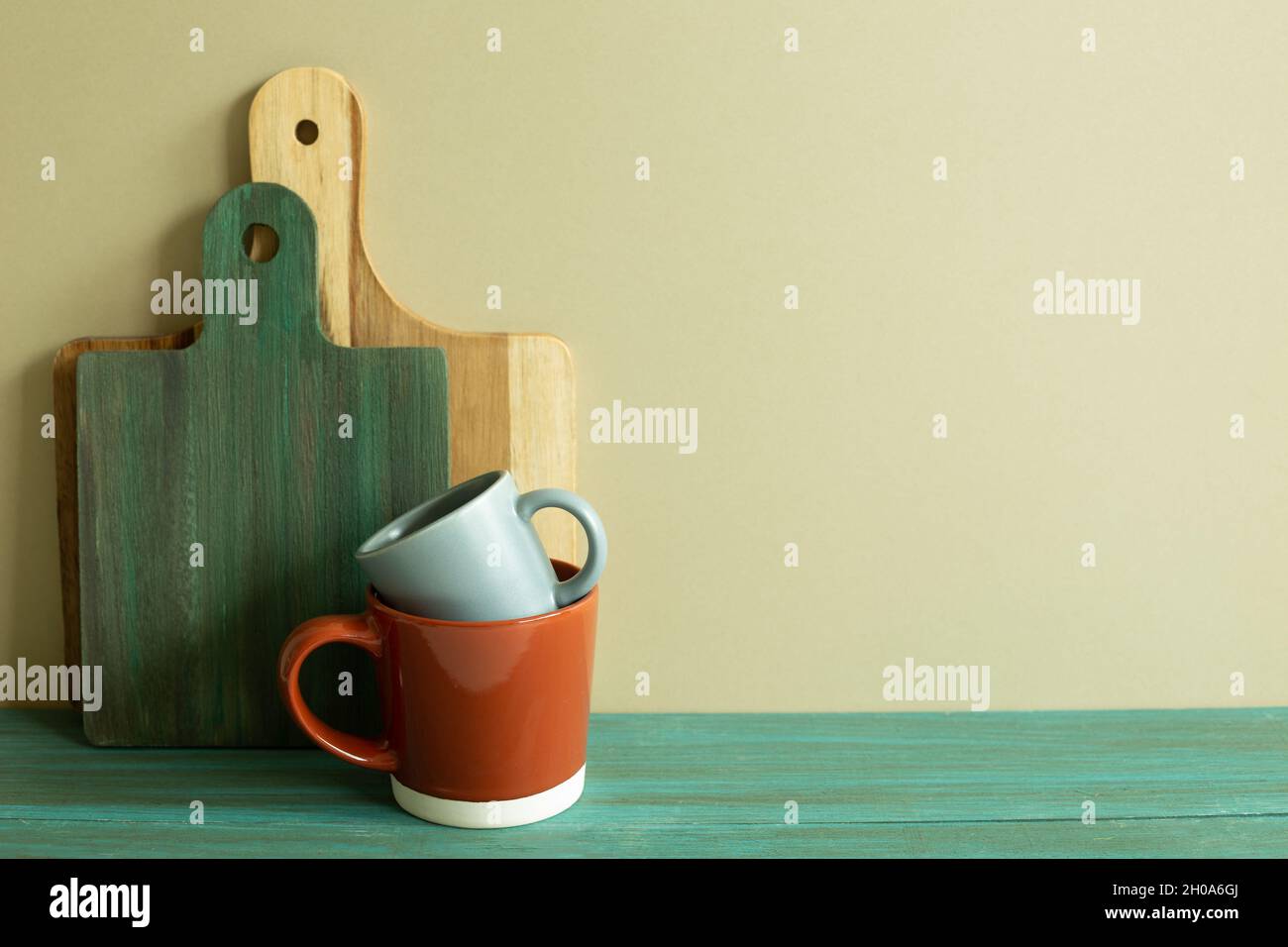 Tazza e vassoio di legno, tagliere su tavola di legno verde. Parete di fondo kaki. Interno cucina Foto Stock