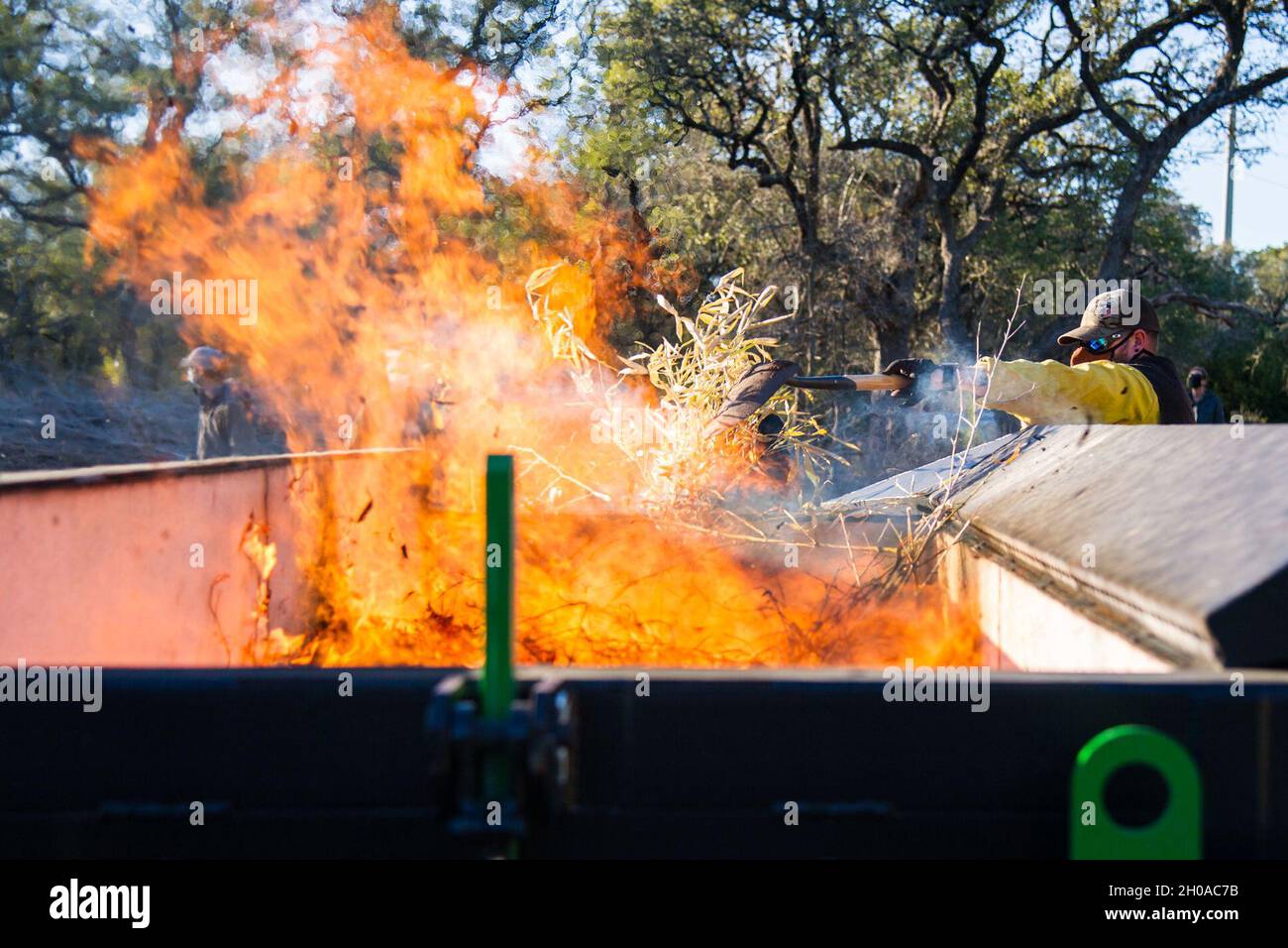 Gli equipaggi di lavoro sono composti da membri dell'802° Ingegnere civile Squadron, Joint base San Antonio Natural Resources Office, Texas A&M Natural Resources Institute e il modulo di supporto JBSA Wildland hanno bruciato pezzi di bambù dorato e pacciame di cedro in un inceneritore a cortina d'aria 7 gennaio 2021 a JBSA-Camp Bullis, Texas. L'inceneritore è progettato per bruciare i detriti di sbarramento in cui le particelle di fumo vengono intrappolate e bruciate, riducendo le particelle di fumo a un limite accettabile consentito dalle linee guida dell'Agenzia per la protezione ambientale. Foto Stock