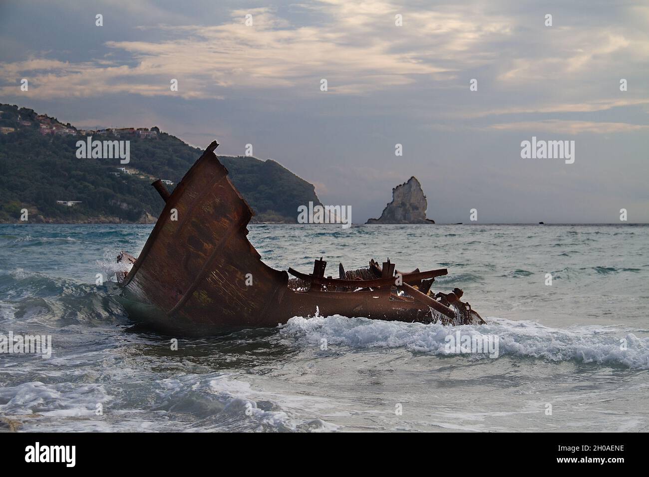 Onde che si infrangono sul relitto arrugginito di una barca da pesca rotta e bloccata Foto Stock