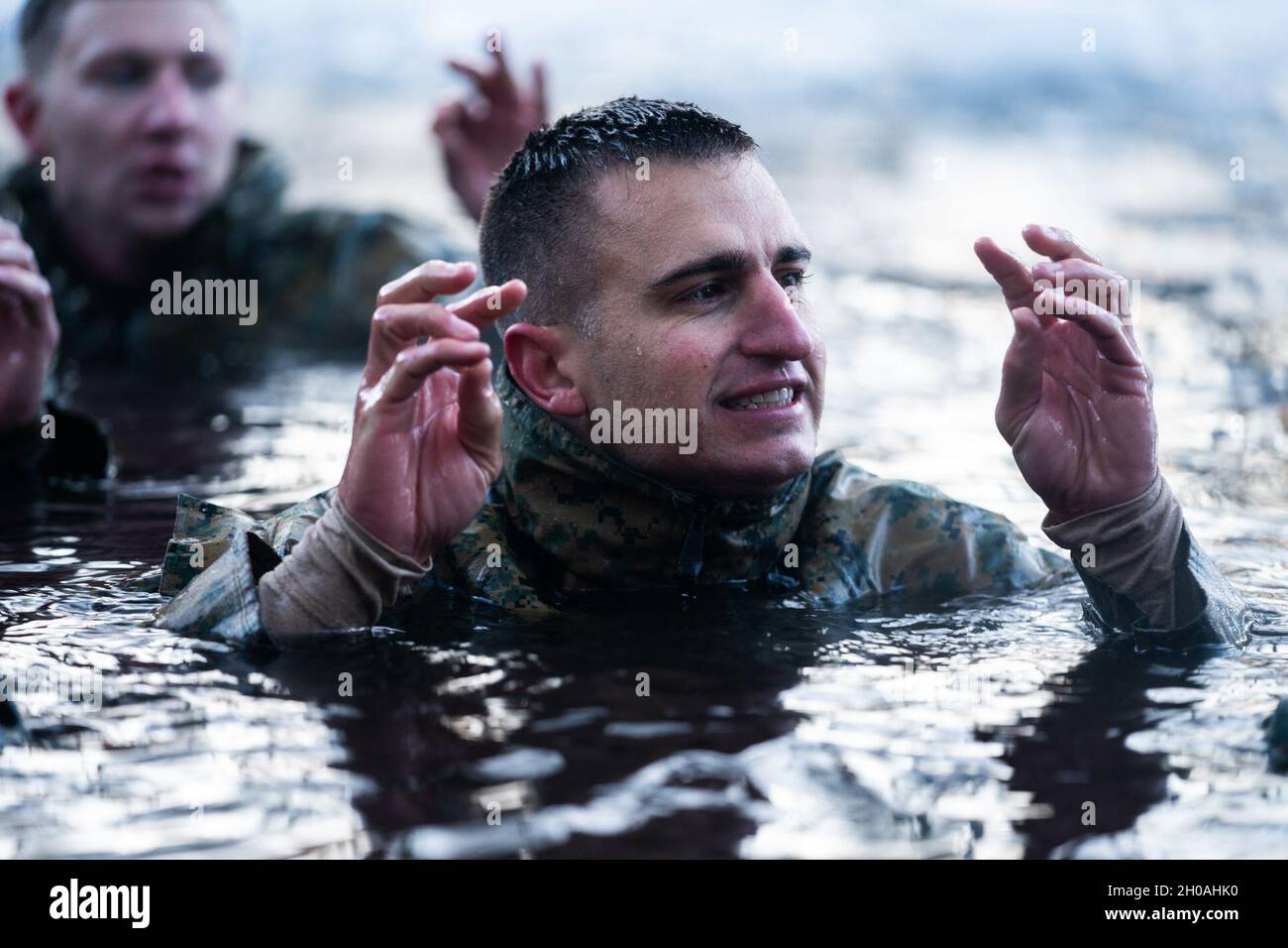 Una Marina degli Stati Uniti controlla la sua destrezza del dito mentre si siede nell'acqua di un laghetto congelato al Marine Corps Mountain Warfare Training Center, California il 9 gennaio 2021. I marinai e i marinai che partecipano al Basic Cold Weather Leaders Course sono tenuti a sottoporsi al laboratorio di ipotermia, un evento di addestramento in cui i marines sperimentano e imparano a combattere l'ipotermia. Foto Stock