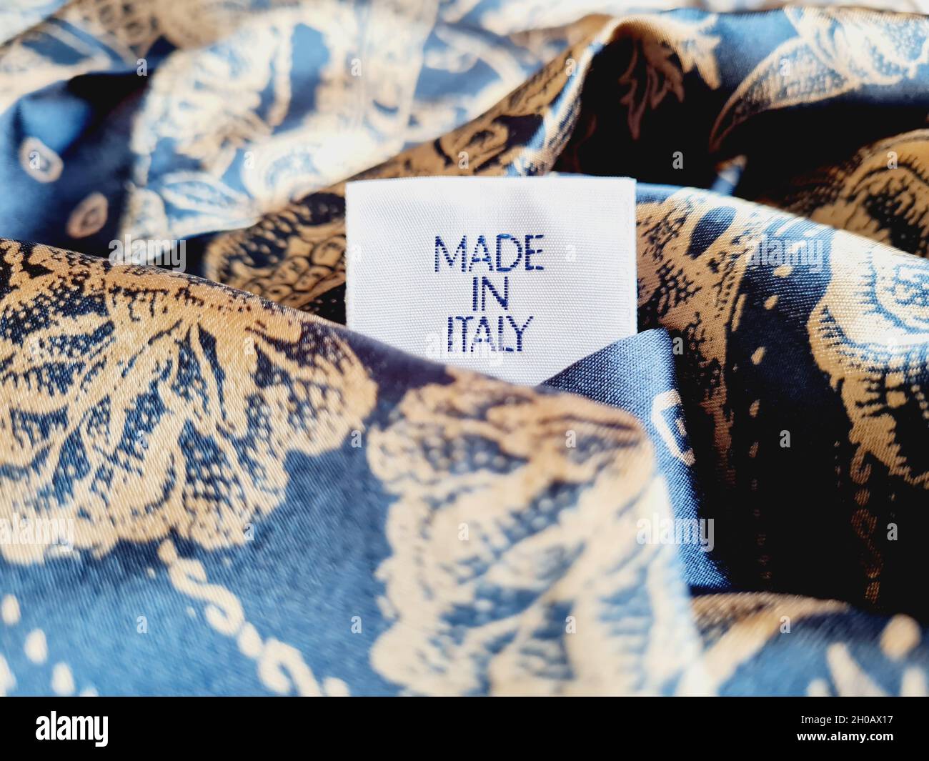 Primo piano di un'etichetta "Made in Italy" su un foulard blu con sfondo sfocato Foto Stock