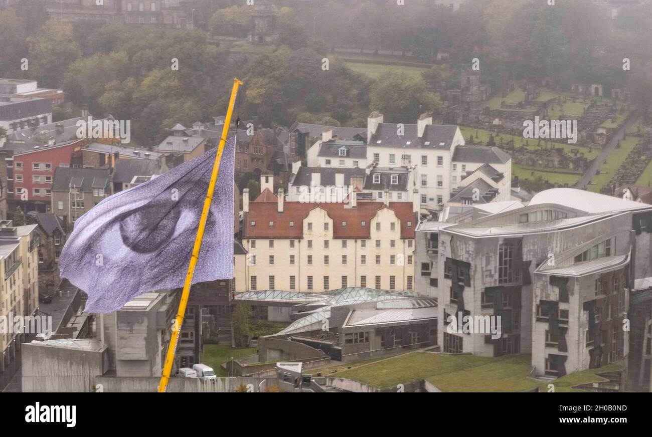Edimburgo , Regno Unito. 12 ottobre 2021 nella foto: L’Artivist svizzero, l’impianto di climatizzazione aerea di Dan Acher stiamo guardando fa la sua prima visita in Scozia prima della COP26. La bandiera globale, con le sue dimensioni di un edificio a 10 piani, presenta un occhio monumentale composto da migliaia di ritratti, provenienti da 190 paesi. Credit: Rich Dyson/Alamy Live News Foto Stock