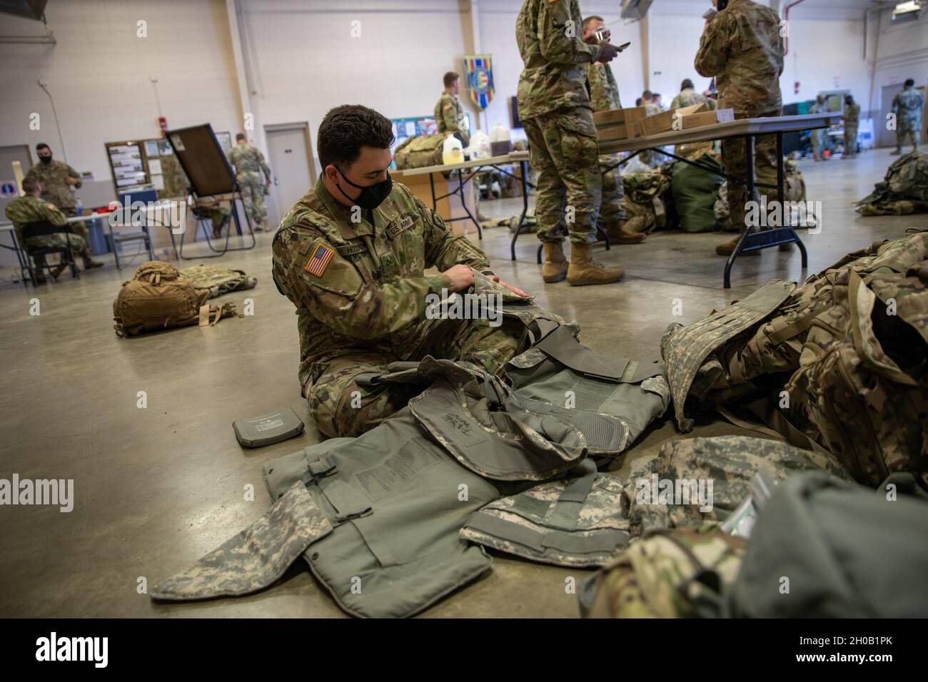 PFC. James Hood un soldato con la 114th Military Police Company, la guardia nazionale dell'esercito del Mississippi, inserisce le armature in un gilet tattico del supporto della piastra nella loro Armory in Clinton, Miss., 14 gennaio 2021. Il 114th MP Co. Si sta preparando a dispiegarsi a Washington, D.C. come Capitol Response per la 59th Inaugurazione Presidenziale. Foto Stock