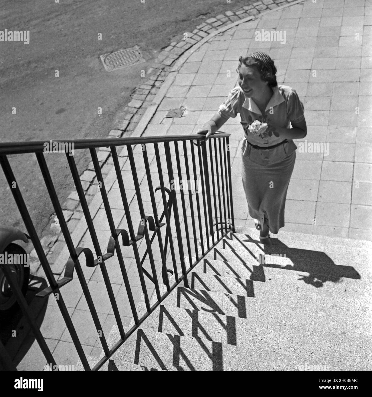 Eine Frau Mit einem Blumenstrauß un einer Treppe in der Innenstadt von Stuttgart, Deutschland 1930er Jahre. Una giovane donna con fiori in corrispondenza di una scala nel centro della città di Stoccarda, Germania 1930s. Foto Stock