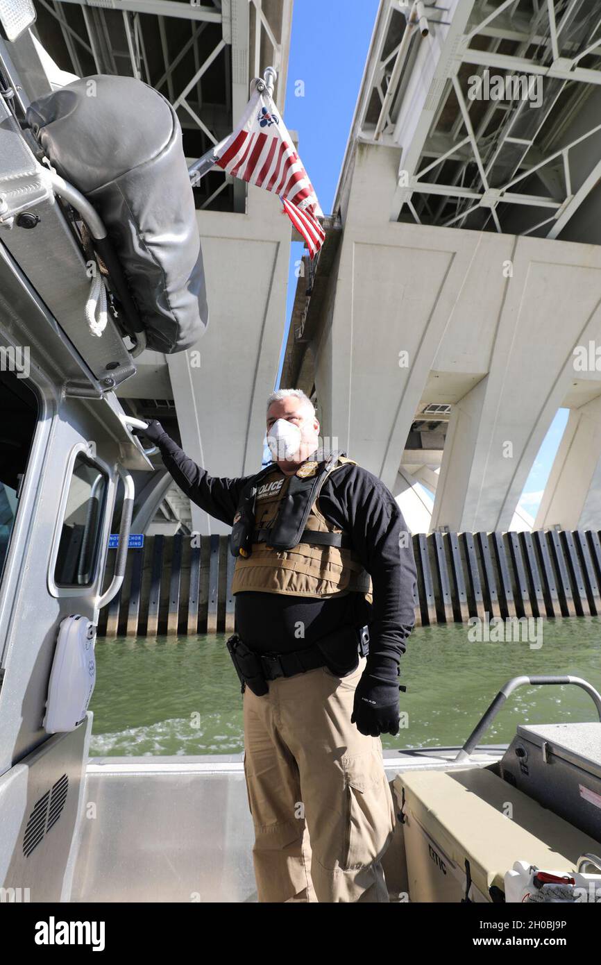 L'agente di interdipendenza navale William Carroll scansiona la zona sicura del fiume mentre la sua nave passa sotto uno dei molti ponti che attraversano il fiume Potomac a Washington D.C., fornendo supporto alle operazioni di sicurezza per la 59a Inaugurazione Presidenziale, il 19 gennaio 2021. Foto CBP di Michael Papa Foto Stock