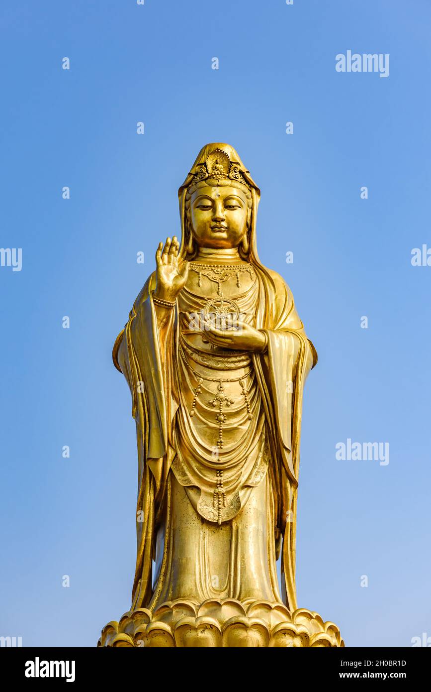 Statua del Buddha di Guan Yin d'oro con cielo blu. Foto Stock