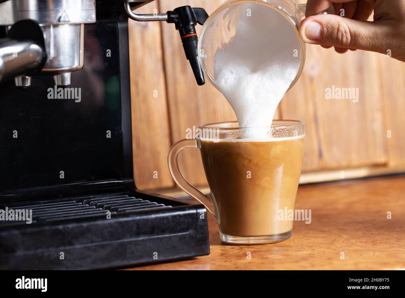 Preparare il caffè con latte per cappuccino in una macchina per cappuccino  con una macchina per cappuccino manuale sullo sfondo di un piano in legno  Foto stock - Alamy