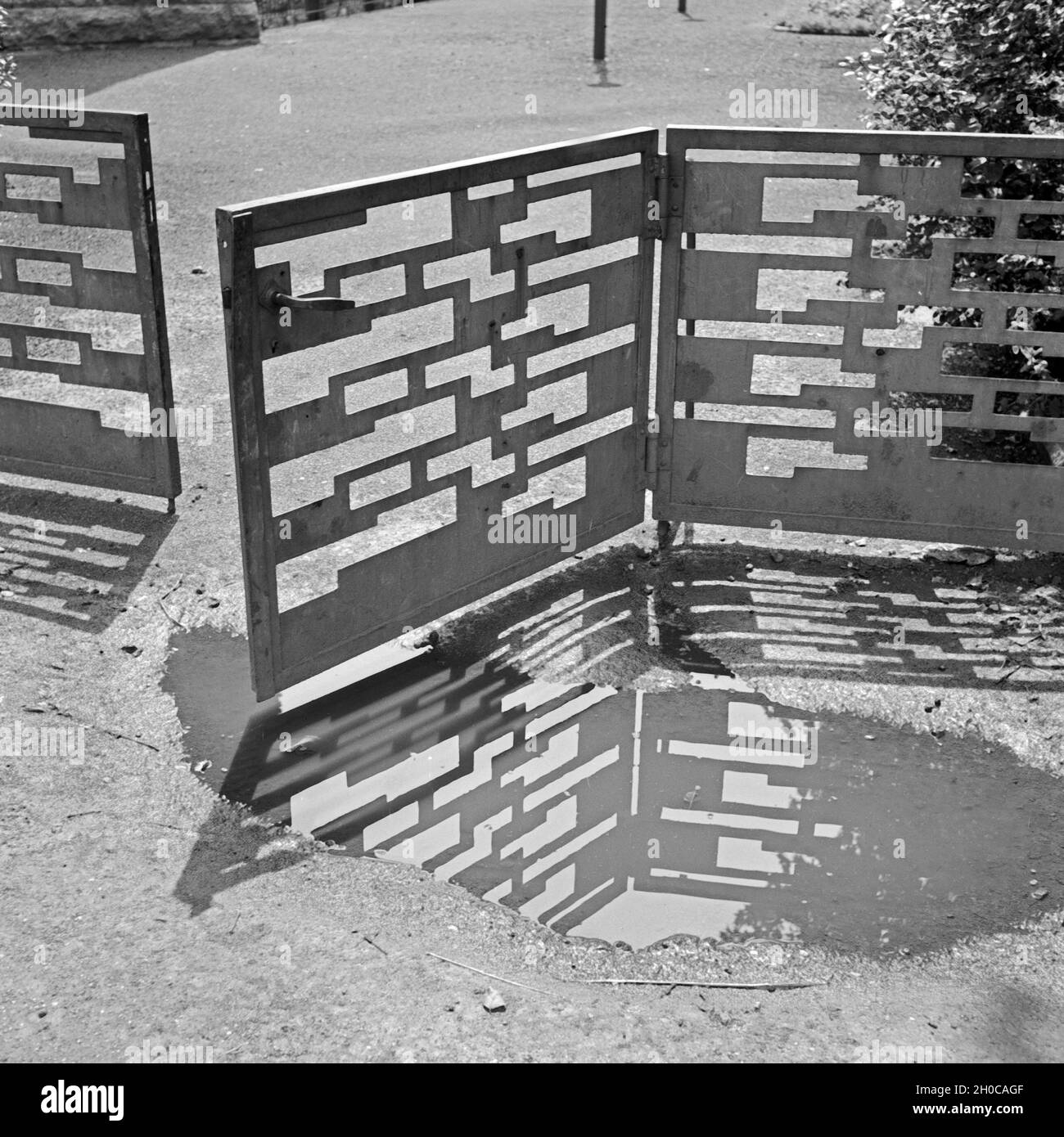 Das Muster eines Durchgangstores in einer Pfütze, Deutschland 1930er Jahre. Un giardino entrata che riflette in una pozza, Germania 1930s. Foto Stock