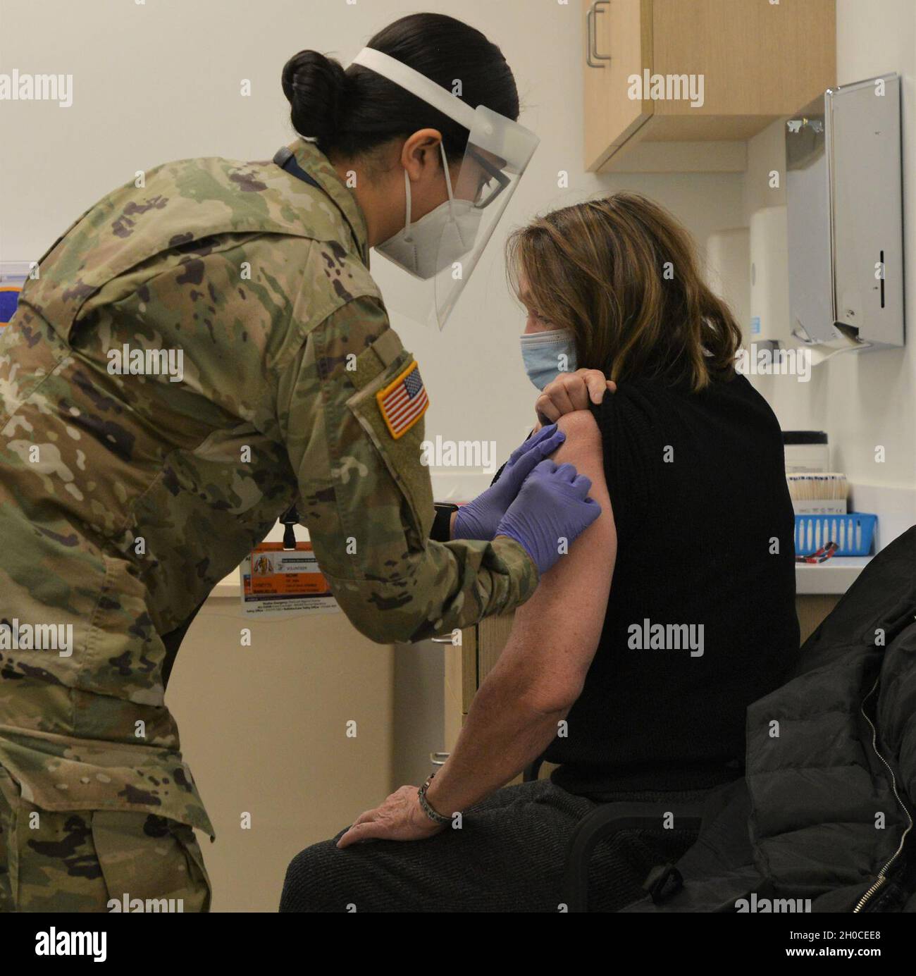 Illinois Army National Guard Medic SPC. Lynnette Banvelos di Addison, Illinois, somministra un vaccino ad un membro della comunità locale al centro sanitario di North Riverside della contea di Cook. I medici dell'esercito ricevono circa quattro mesi di addestramento intensivo nelle mansioni mediche a Fort Sam Houston, Texas, compreso la somministrazione delle vaccinazioni. Dopo la loro formazione iniziale, i medici sono tenuti a ri-certificare periodicamente. In Illinois, i medici sono certificati dallo stato a livello EMT, ma la loro formazione Army include anche compiti a livello paramedico più avanzato. Illinois Governor JB Pritzker attiva Foto Stock