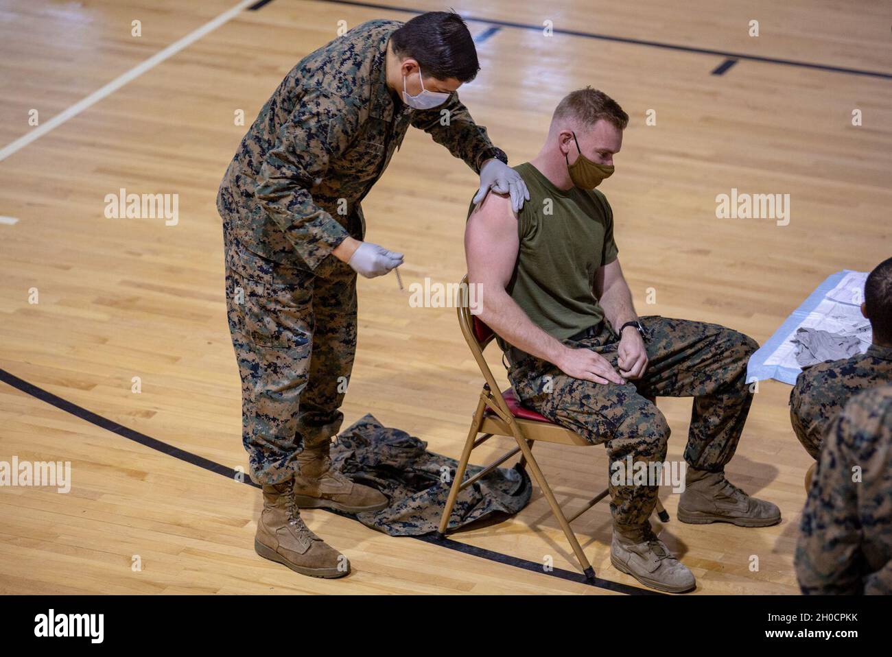 U.S. Navy Hn. David A. Garcia, a sinistra, un corpsman con il secondo battaglione medico, somministra il vaccino COVID-19 ad una Marina degli Stati Uniti, a destra, con il 1° battaglione, il 6° reggimento marino, la 2° divisione marina a Goettge Memorial Field House sul Marine Corps base Camp Lejeune, North Carolina, 25 gennaio 2021. Al fine di facilitare una produzione massima di personale della II forza di spedizione marina, la casa da campo è stata temporaneamente riconfigurata dalla base per fungere da centro di vaccinazione COVID-19 esclusivamente per loro. Foto Stock