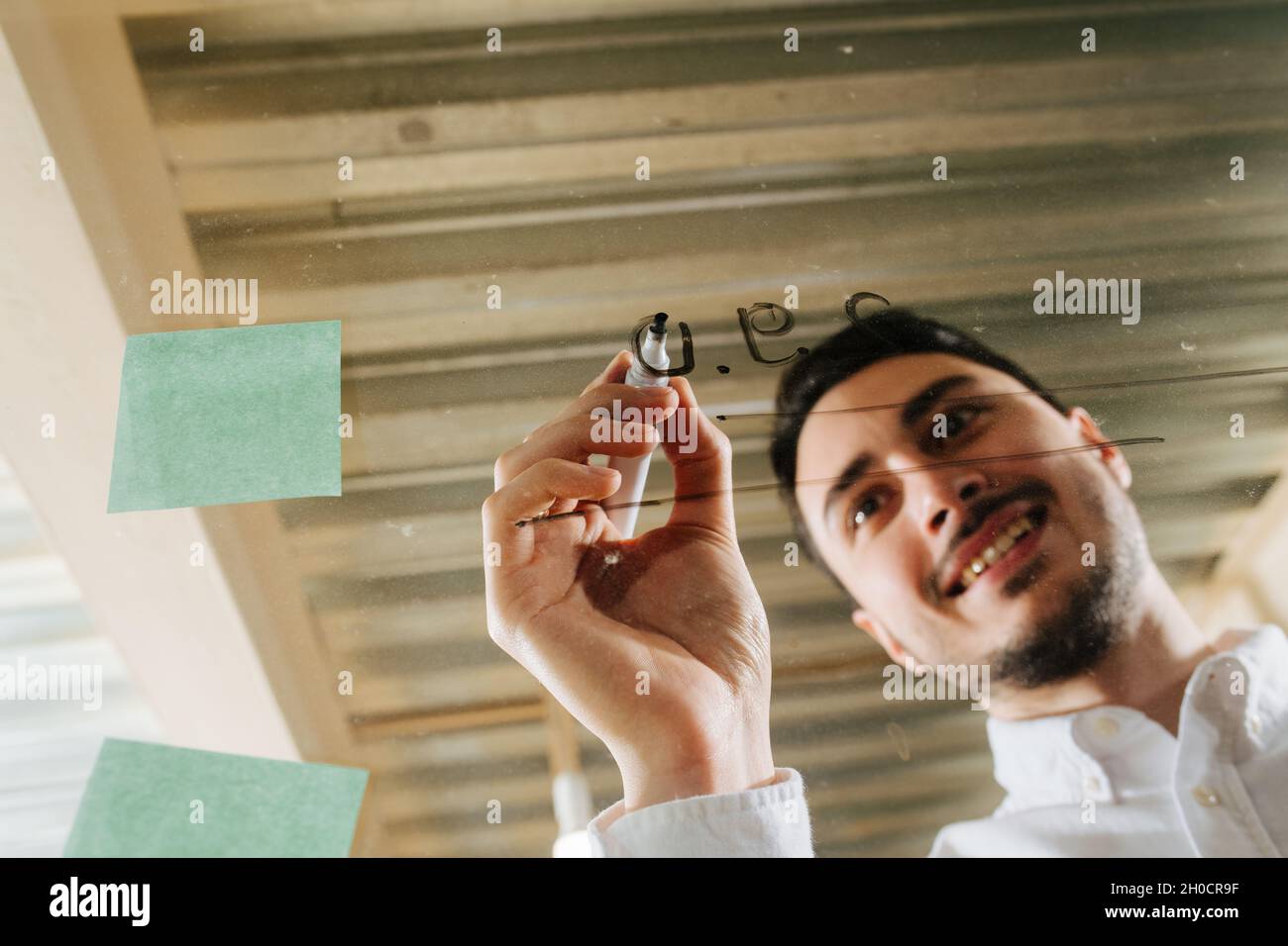 Immagine di un giovane manager con un abito in una maglietta che scrive su un pannello di plastica trasparente. Vista frontale. Foto Stock