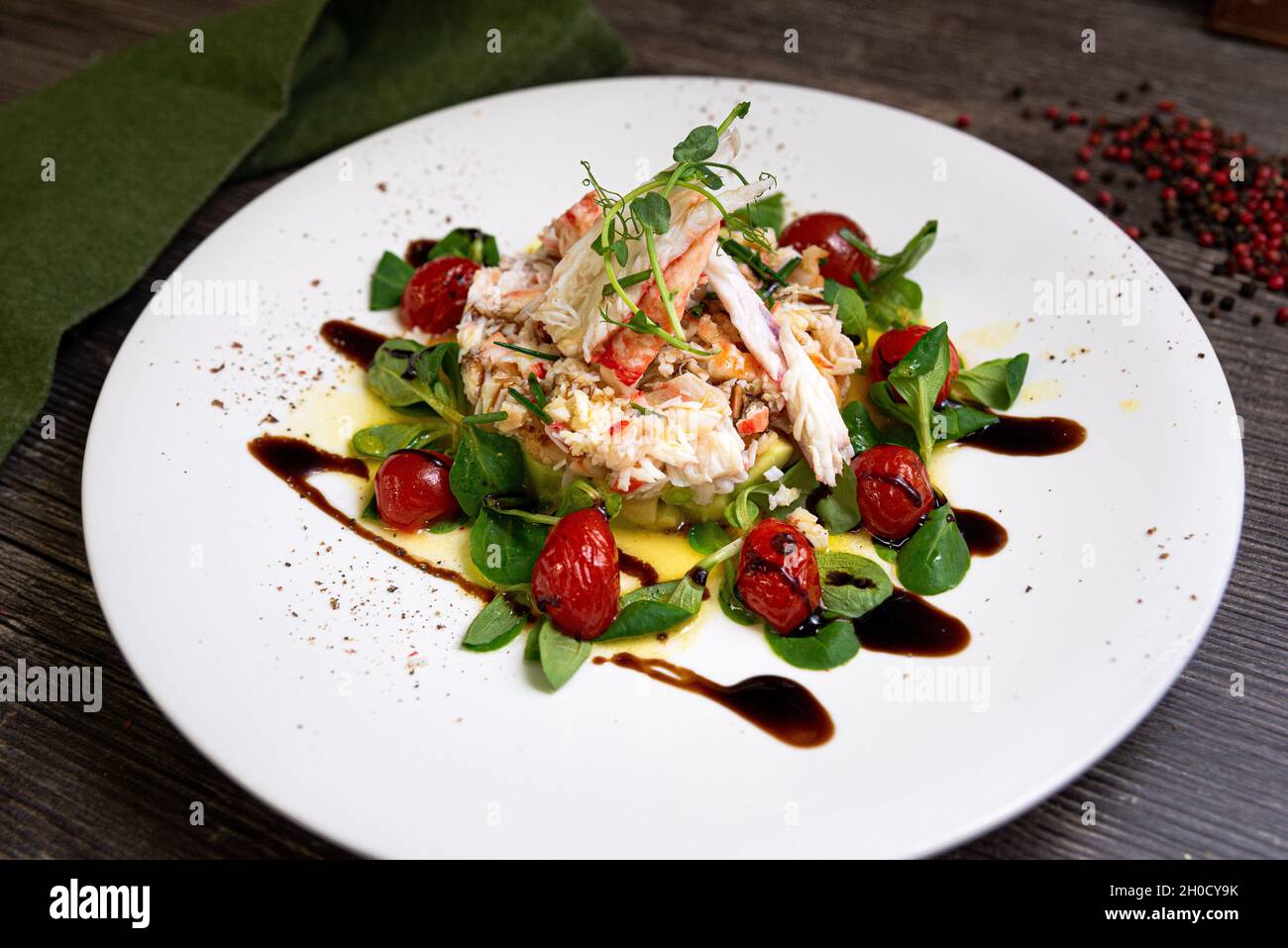 Insalata con granchio, cetriolo, gamberi da cocktail, tartaro di avocado e salsa di mango. Grande piatto di cibo. Insalata condita con olio d'oliva, salsa balsamica. Foto Stock