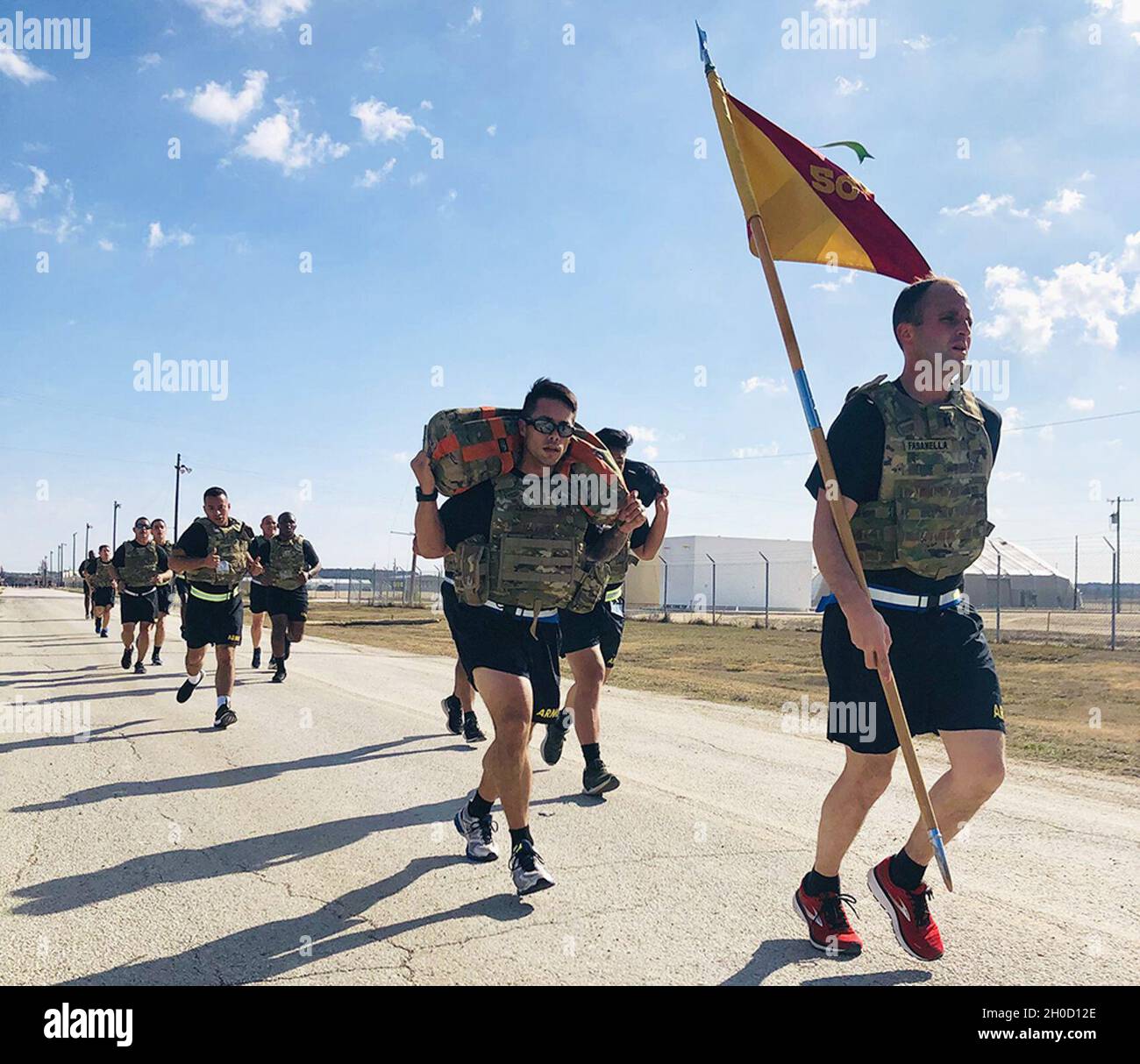 Nicholas Fasanella, comandante della società con sede centrale per il cinquantesimo gruppo di supporto regionale (RSG), trasporta il guidon della sua unità durante un'unità gestita a Fort Hood, Texas, il 27 gennaio 2021. Fasanella e i soldati raffigurati si stanno allenando per i test Expert Soldier Badge, correndo in giubbotti tattici esterni migliorati e portando a turno una borsa di sabbia da 50 libbre, che l'Esercito i Lt. Gabriel Perez ha sulle sue spalle. Foto Stock