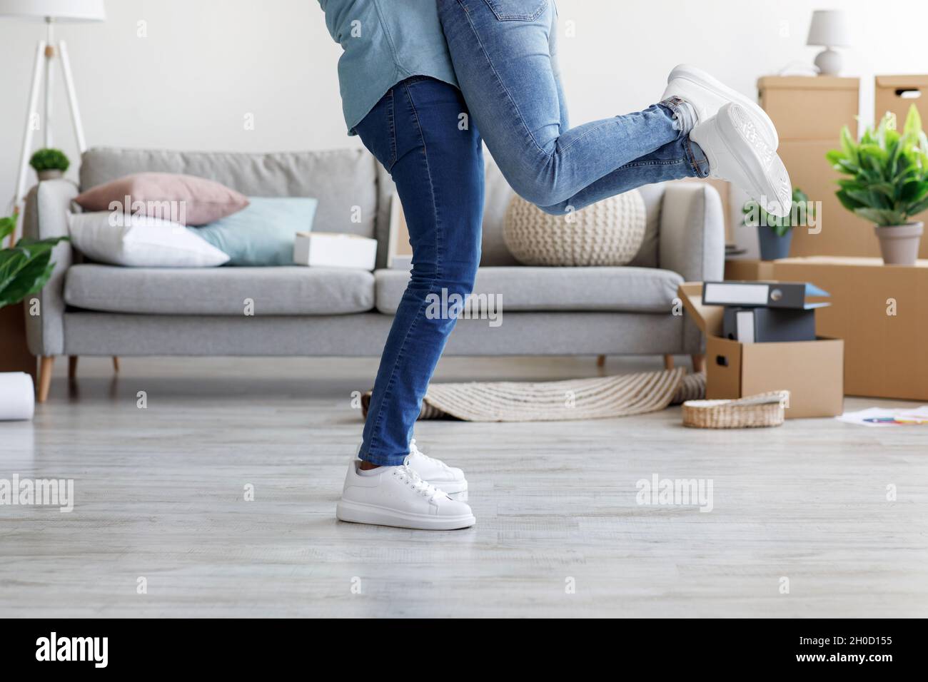 Corto giovane nero maschio abbracci e solleva donna in proprio appartamento con scatole di cartone Foto Stock