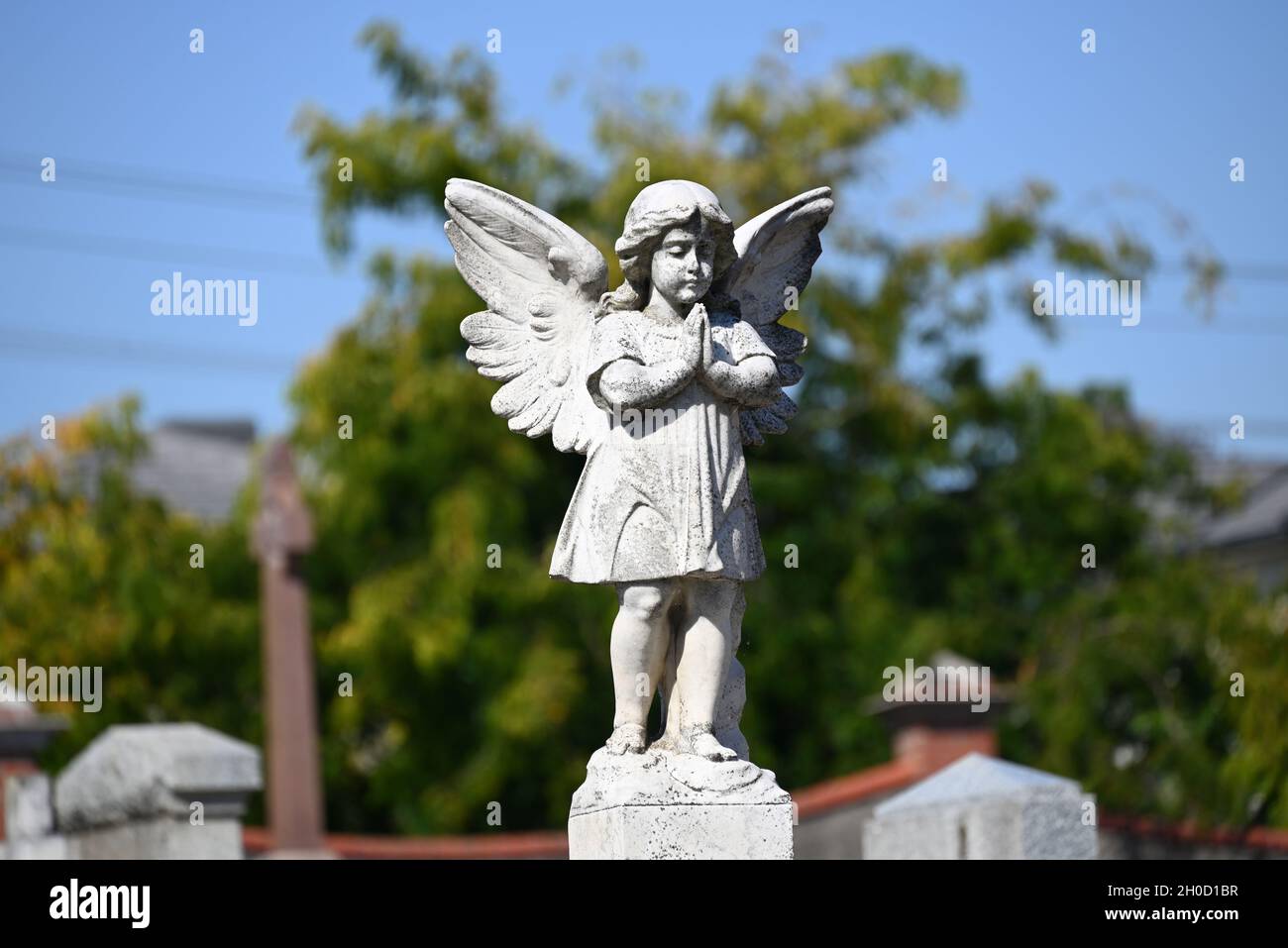 Una scultura di un cherubino in preghiera in un cimitero durante una giornata di sole Foto Stock