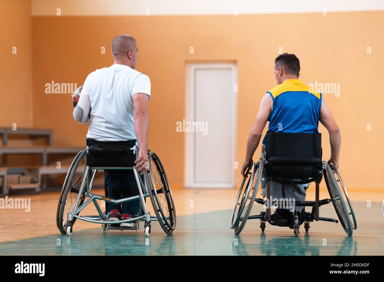 I veterani della guerra disabili hanno mescolato le squadre di pallacanestro di età e di corsa in carrozzina che giocano un match di addestramento in una sala della palestra di sport. Disabili Foto Stock