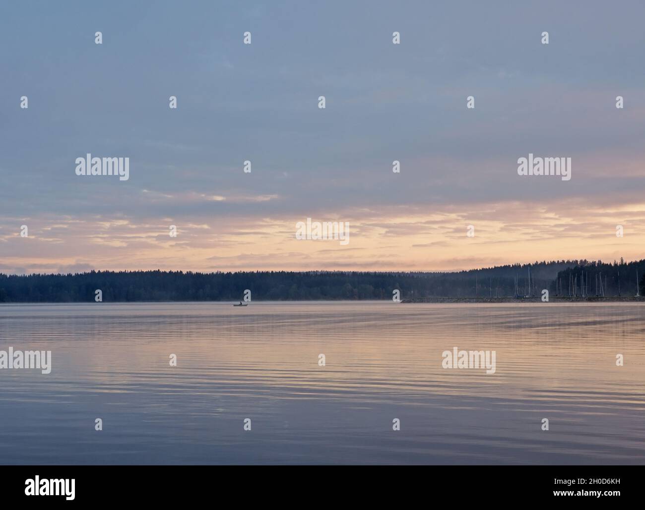 Pescatore in barca la mattina presto sul lago Lipno nelle montagne Sumava, Repubblica Ceca Foto Stock