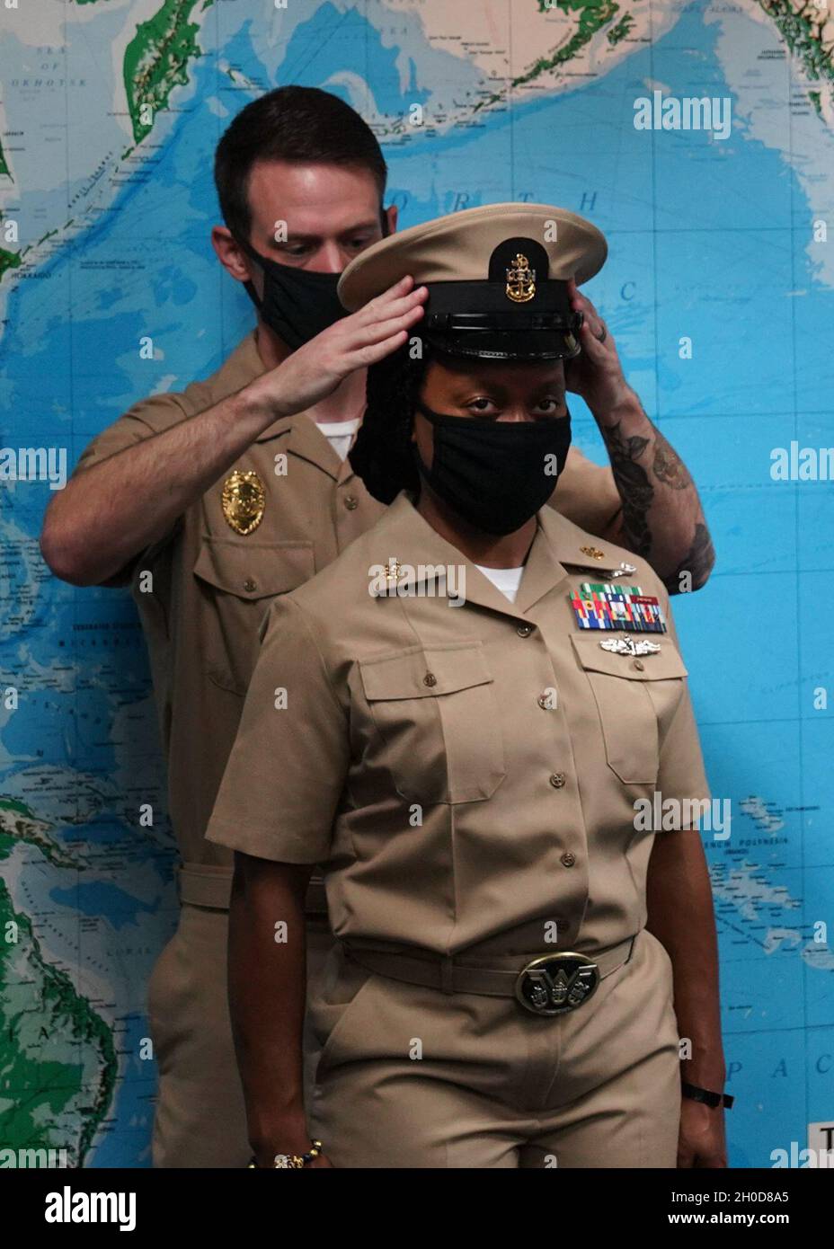 SINGAPORE (Gen. 29, 2021) – Craig Lusk, Chief Master-at-Arms, stende una copertina sul Chief Information Systems Technician Kara Walker durante una cerimonia di imbottigliamento del Chief Petty Officer nella sala conferenze Commander, Logistics Group Western Pacific. Foto Stock