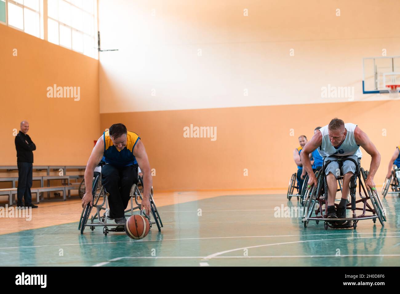 I veterani della guerra disabili hanno mescolato le squadre di pallacanestro di età e di corsa in carrozzina che giocano un match di addestramento in una sala della palestra di sport. Disabili Foto Stock