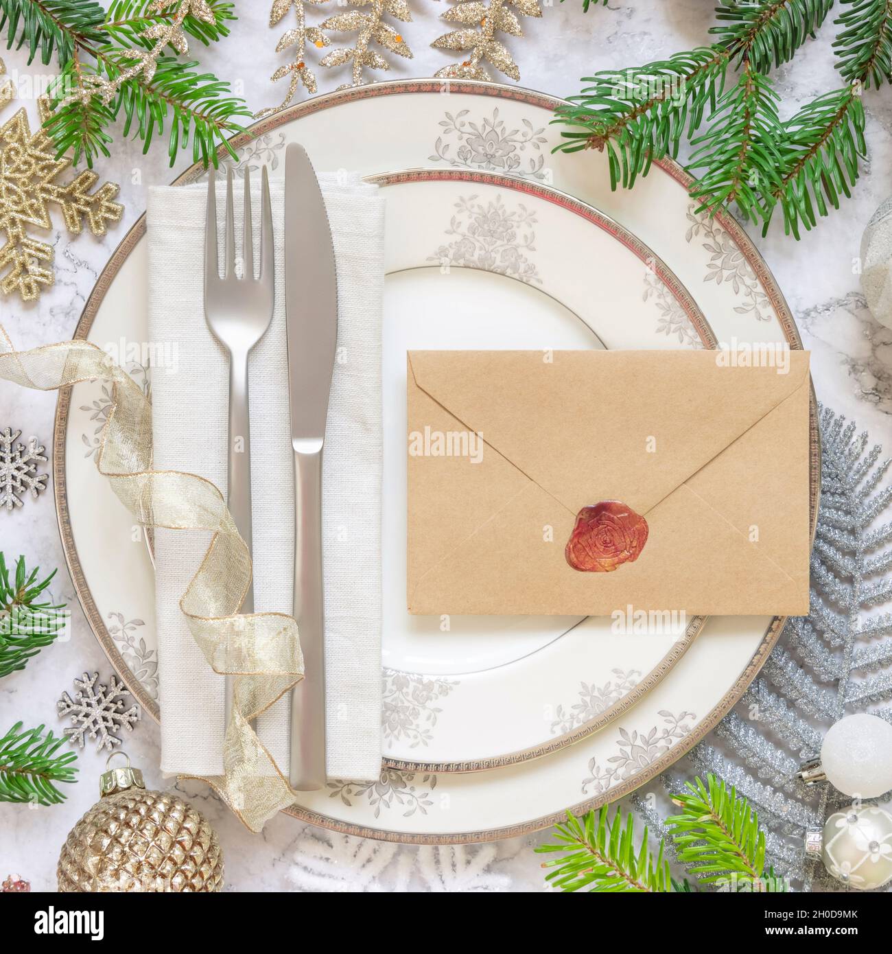 Tavolo festivo con ornamenti, rami di abete e vista dall'alto busta sigillata. Mockup di Natale o Capodanno busta su bianco tavolo in marmo f Foto Stock