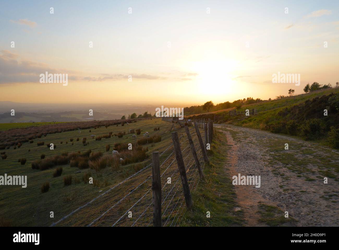 Una corsia di campagna a Rivington, vicino a Bolton, offre una splendida vista sul tramonto del sole nella valle sottostante. Foto Stock